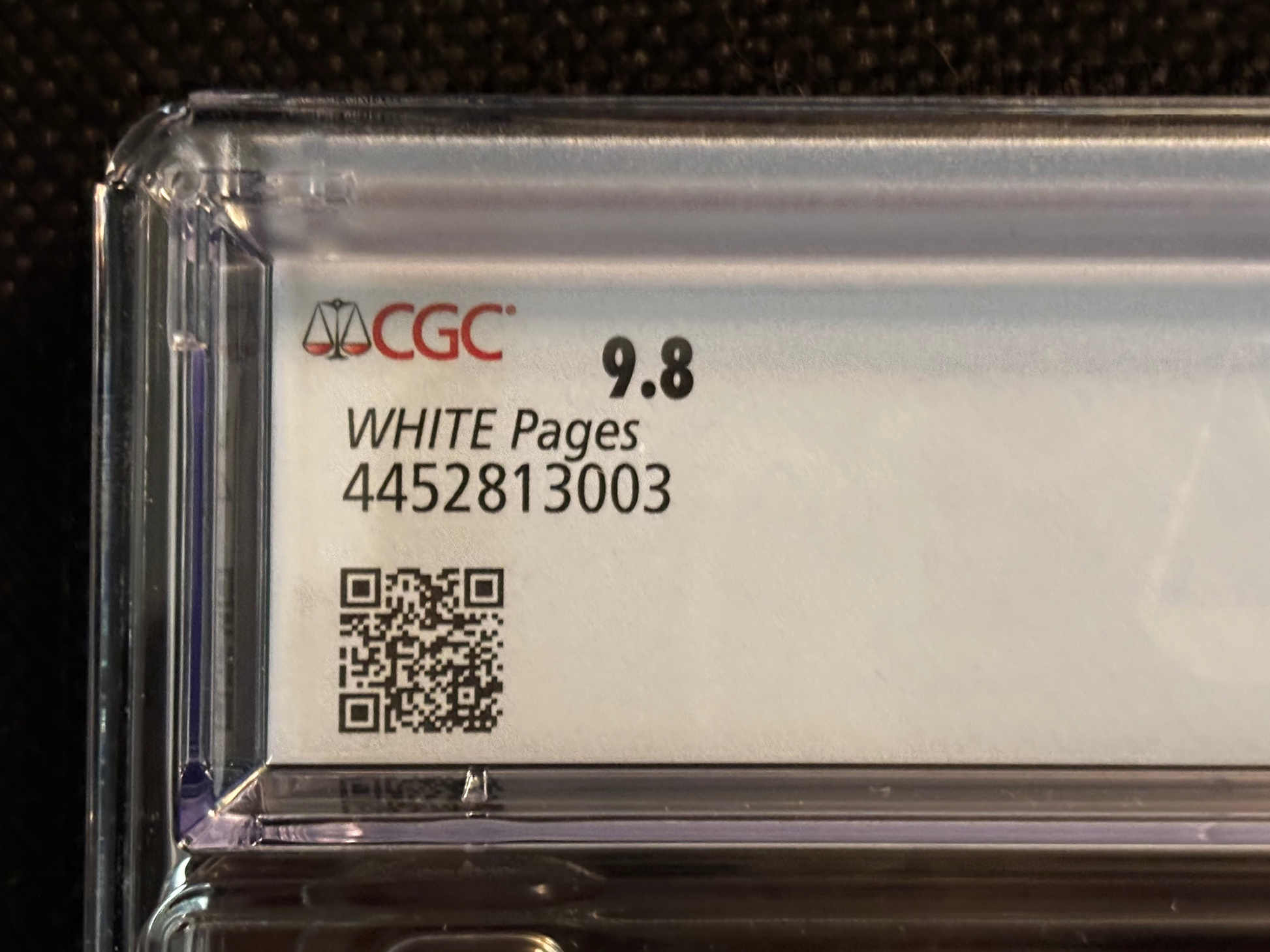 Card with a CGC logo, QR code, and text on a clear plastic holder against a dark background